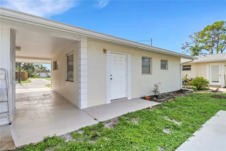 Doorway to property with stucco siding and an attached carport