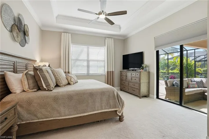 Bedroom with a tray ceiling, carpet flooring, ornamental molding, access to outside, and a ceiling fan