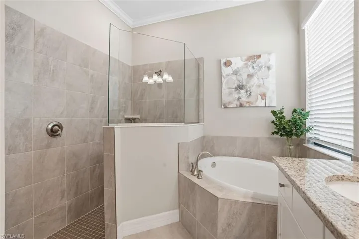 Full bathroom featuring a garden tub, a walk in shower, vanity, ornamental molding, and tile patterned flooring