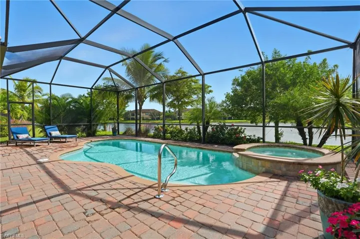 View of pool with a sunroom, a pool with connected hot tub, a water view, glass enclosure, and a patio area