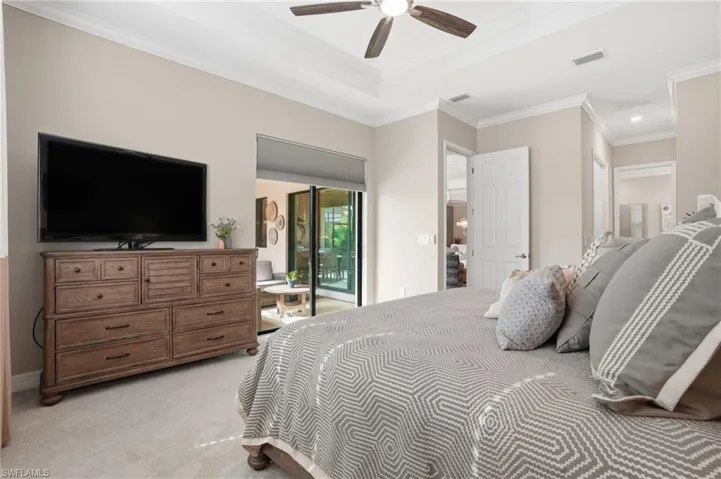 Bedroom with crown molding, light carpet, access to exterior, ceiling fan, and a raised ceiling