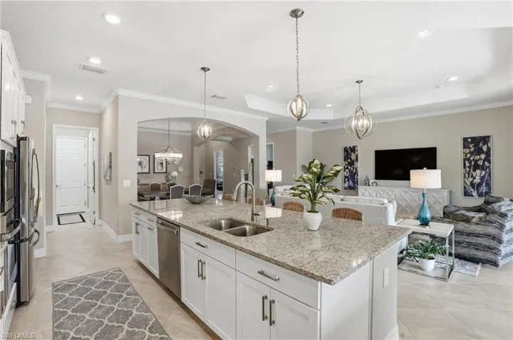 Kitchen with a chandelier, white cabinetry, open floor plan, light stone counters, and arched walkways