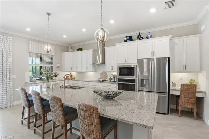 Kitchen with a breakfast bar, white cabinets, appliances with stainless steel finishes, decorative backsplash, and ornamental molding