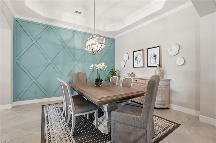 Dining space featuring ornamental molding, a tray ceiling, and a chandelier