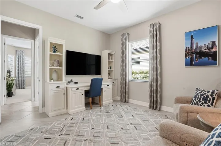 Home office featuring built in desk, ceiling fan, and light tile patterned flooring
