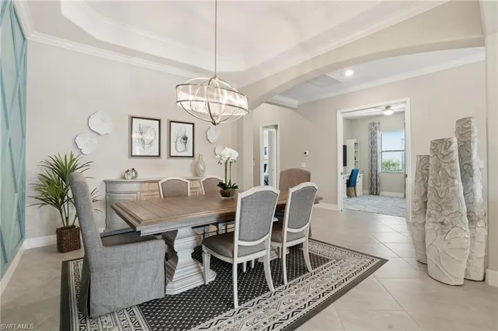 Dining area featuring ornamental molding, arched walkways, light tile patterned floors, and ceiling fan