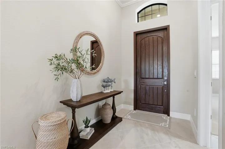 Entryway with light tile patterned flooring and ornamental molding