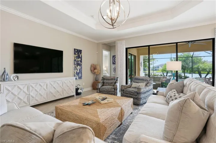 Living room with crown molding, a tray ceiling, tile patterned floors, and a chandelier