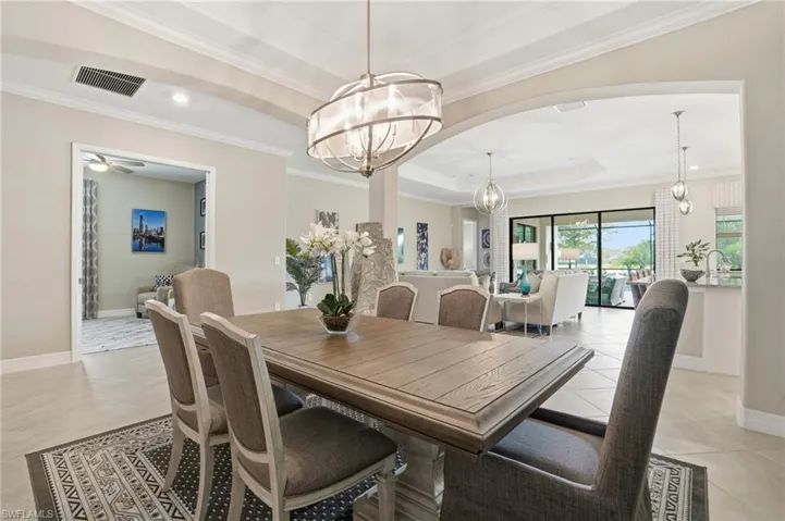 Dining room featuring a tray ceiling, ornamental molding, a chandelier, light tile patterned flooring, and recessed lighting