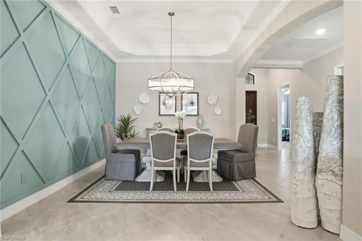 Dining area featuring arched walkways, crown molding, light tile patterned flooring, and a tray ceiling