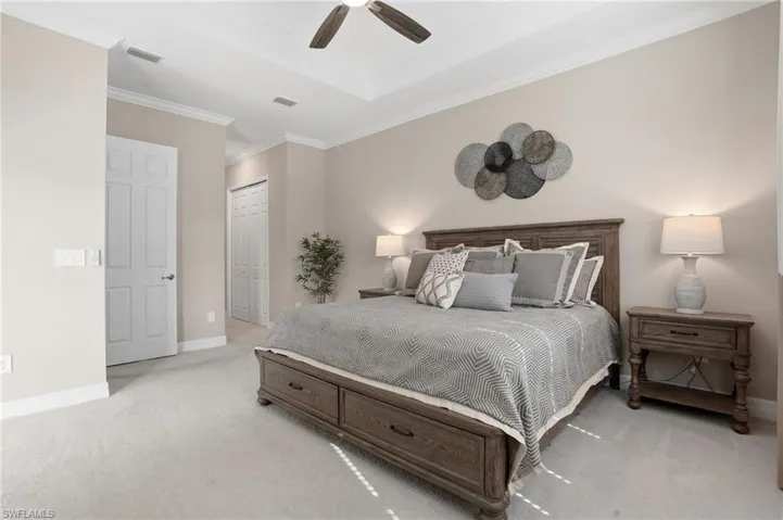 Bedroom with crown molding, light carpet, a ceiling fan, and a closet