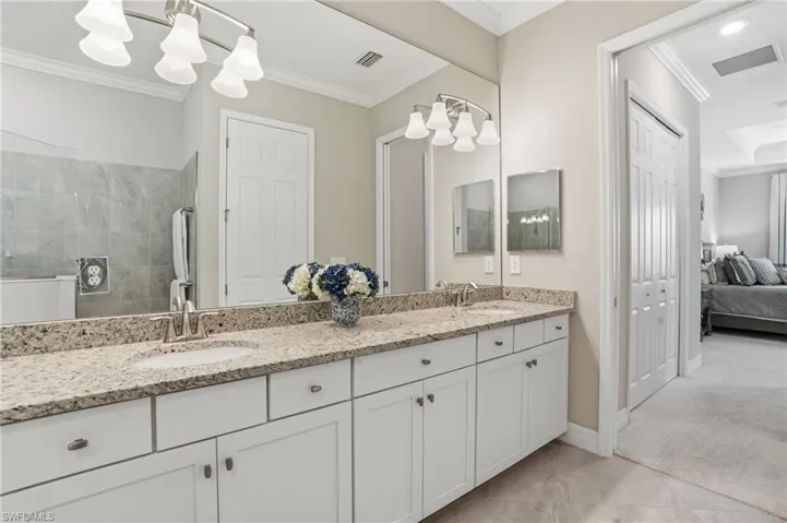 Bathroom with double vanity, ornamental molding, a tile shower, connected bathroom, and light tile patterned flooring