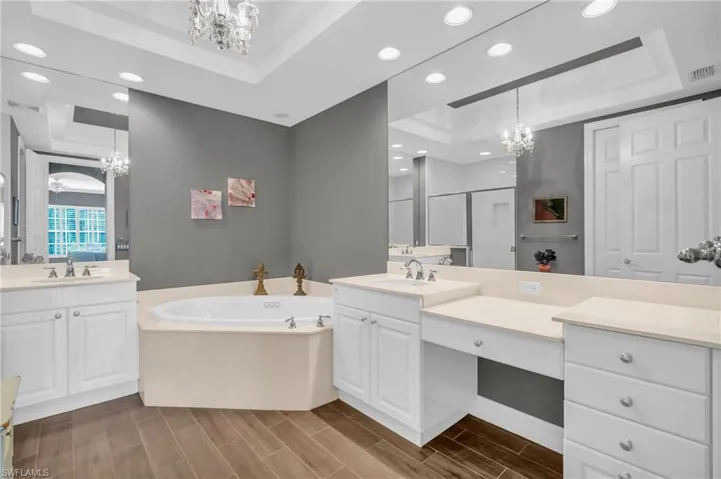 Bathroom featuring vanity, shower with separate bathtub, a raised ceiling, and a chandelier