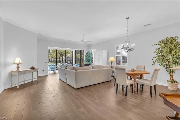 Living room with crown molding, ceiling fan with notable chandelier, and light wood-type flooring