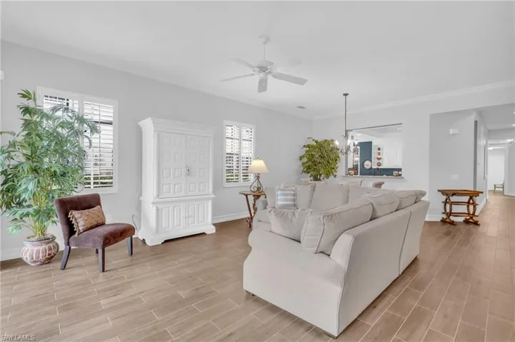 Living room featuring ornamental molding, plenty of natural light, and ceiling fan with notable chandelier
