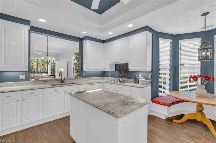 Kitchen with decorative light fixtures, sink, white cabinets, a chandelier, and breakfast area