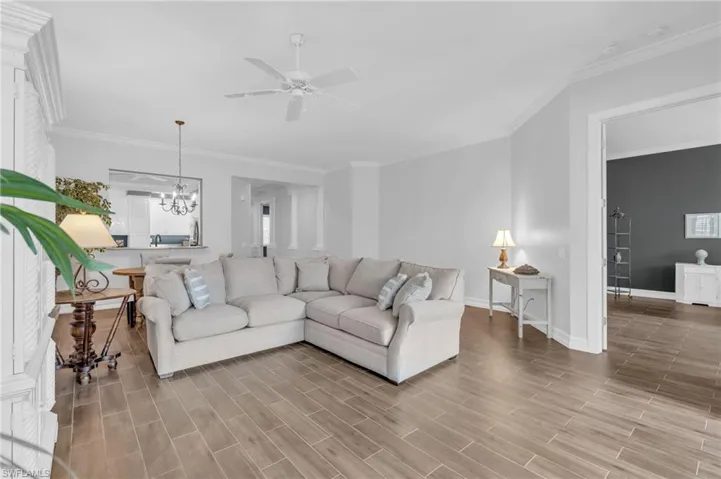 Living room with crown molding and ceiling fan with notable chandelier