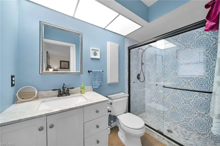 Bathroom featuring hardwood / wood-style floors, vanity, toilet, and a shower with shower door
