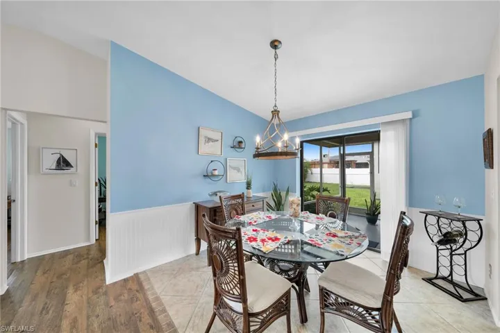 Dining room with vaulted ceiling, an inviting chandelier, and light hardwood / wood-style floors