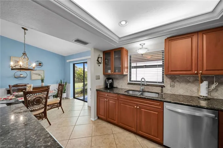 Kitchen featuring pendant lighting, dark stone counters, sink, and stainless steel dishwasher