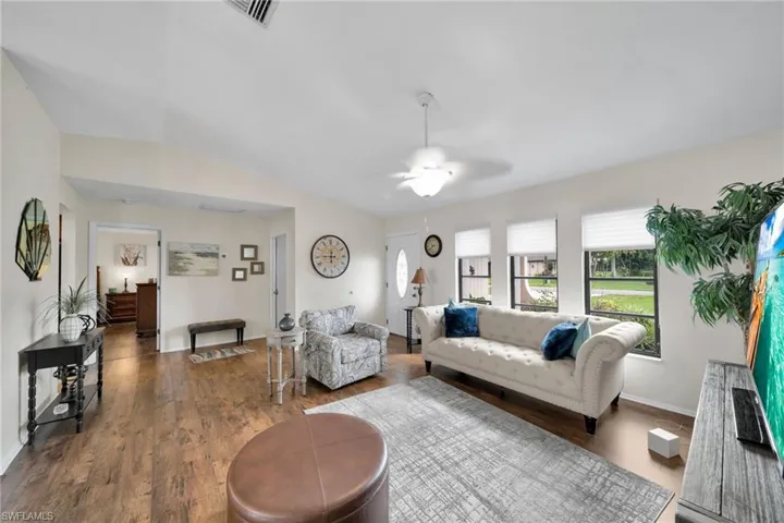 Living room featuring lofted ceiling, dark hardwood / wood-style floors, and ceiling fan