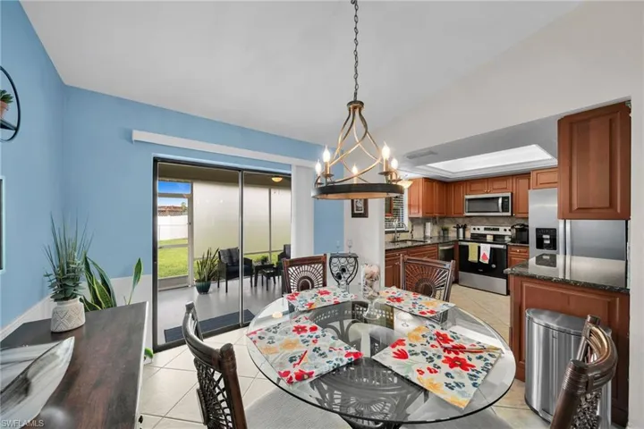 Dining area featuring lofted ceiling, light tile patterned flooring, sink, and a chandelier