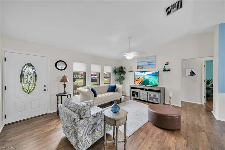 Living room featuring ceiling fan, lofted ceiling, and dark wood-type flooring