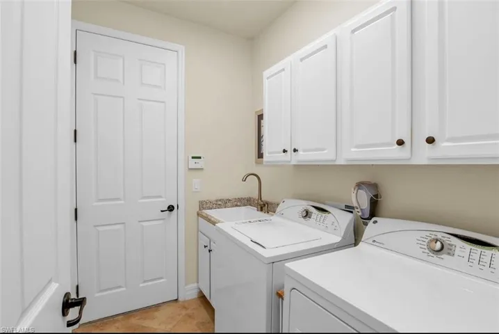 Laundry area featuring a sink, cabinet space, washing machine and dryer, and light tile patterned flooring