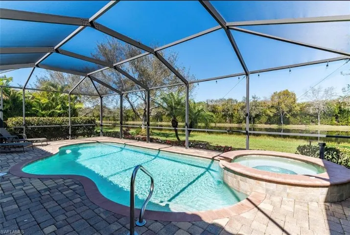 View of swimming pool featuring a pool with connected hot tub, a lanai, and a patio area