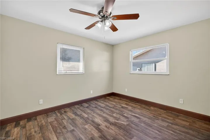 Empty room with dark wood-style flooring and a ceiling fan