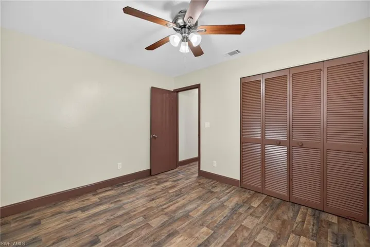 Unfurnished bedroom with dark wood-type flooring, a closet, and a ceiling fan