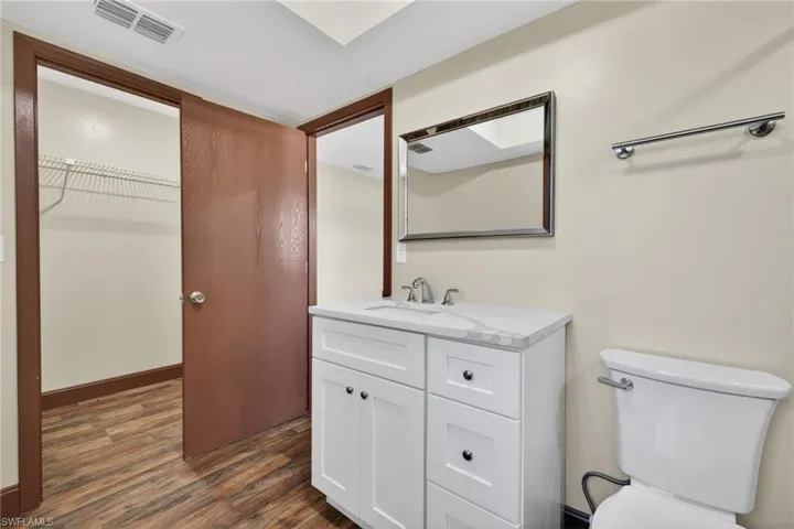 Half bathroom featuring vanity, dark wood-style floors, and a walk in closet
