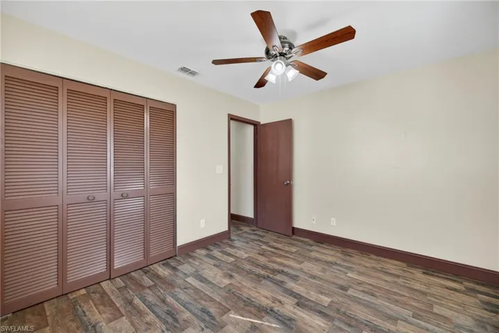 Unfurnished bedroom with dark wood-style flooring, a closet, and ceiling fan