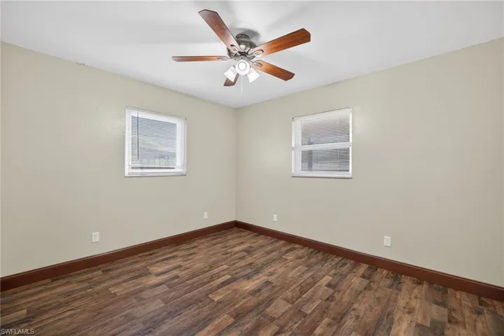 Empty room featuring dark wood-style flooring and a ceiling fan