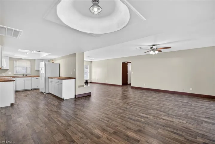 Unfurnished living room with dark wood finished floors and a ceiling fan