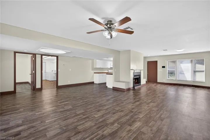 Unfurnished living room featuring dark wood-style flooring, a ceiling fan, a fireplace, and washer / clothes dryer