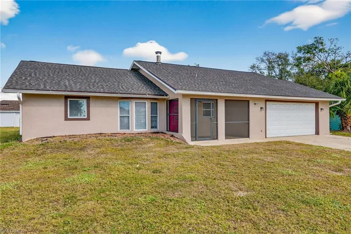 View of front facade with stucco siding, a front yard, an attached garage, and concrete driveway
