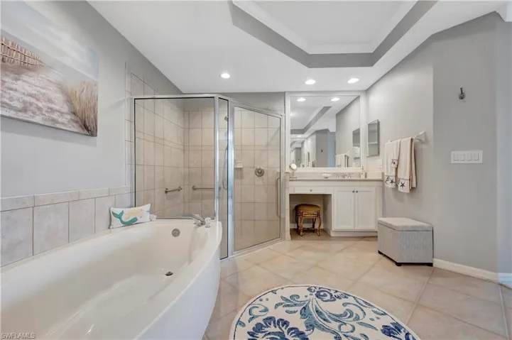 Bathroom featuring shower with separate bathtub, a raised ceiling, vanity, crown molding, and tile patterned flooring
