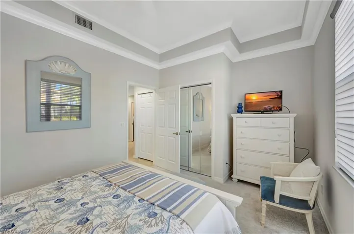Bedroom with crown molding, light carpet, and a closet