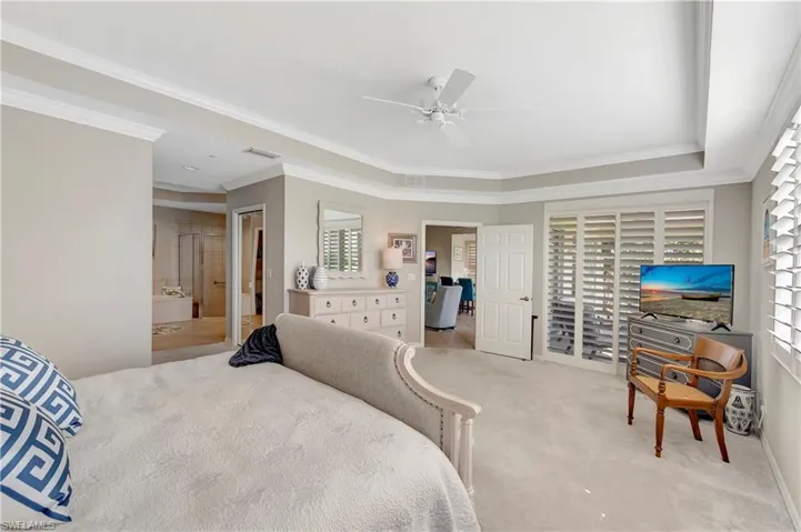 Bedroom featuring dual walk-in closets, ensuite bath, crown molding and plantation shutters