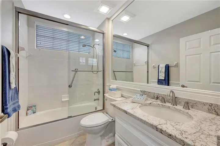 Full bathroom featuring vanity, toilet, tile patterned floors, and combined bath / shower with glass door