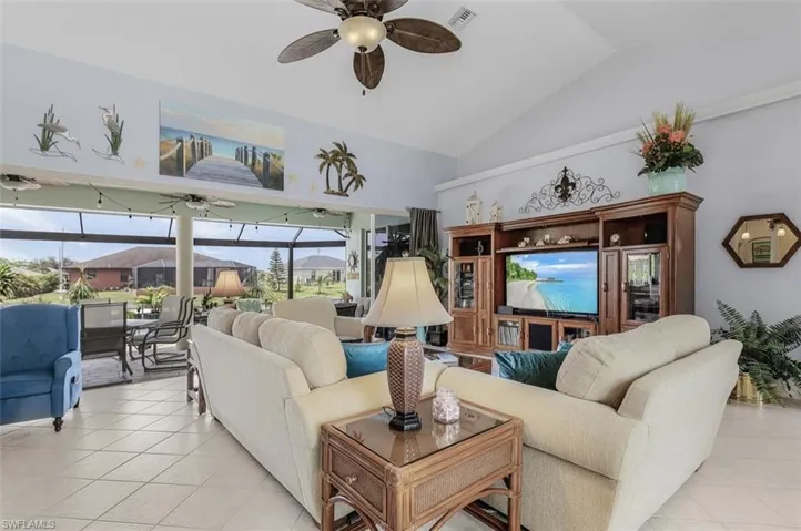 Tiled living room featuring lofted ceiling, a healthy amount of sunlight, and ceiling fan