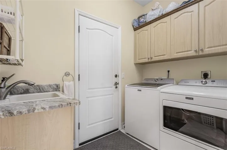 Washroom with sink, washing machine and dryer, and cabinets