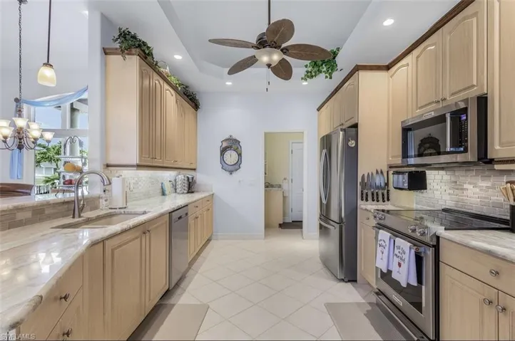 Kitchen featuring appliances with stainless steel finishes, decorative light fixtures, tasteful backsplash, and sink