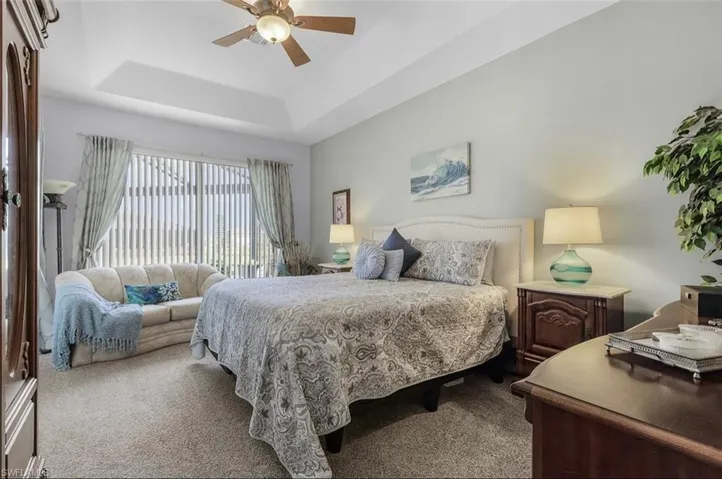 Bedroom featuring a raised ceiling, carpet, and ceiling fan