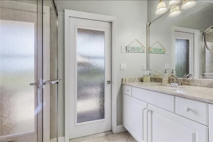 Bathroom with walk in shower, vanity, and tile patterned flooring