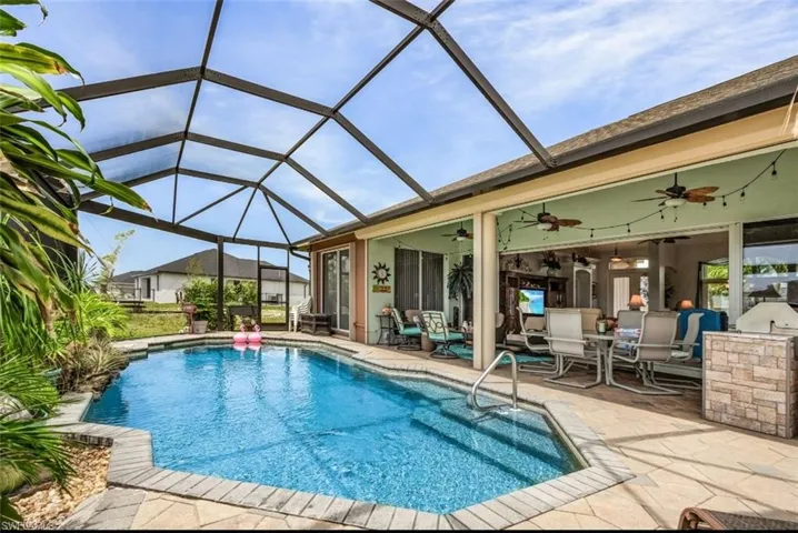 View of swimming pool featuring ceiling fan, a lanai, and a patio area