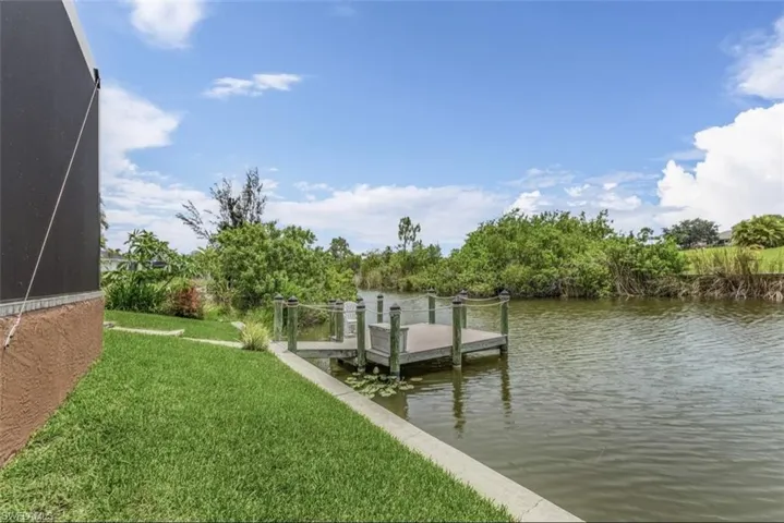 Dock area with a lawn and a water view