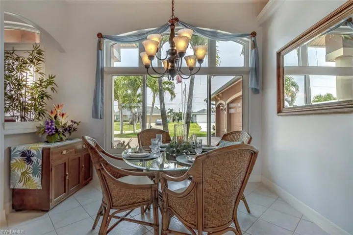 Tiled dining space featuring a notable chandelier and plenty of natural light