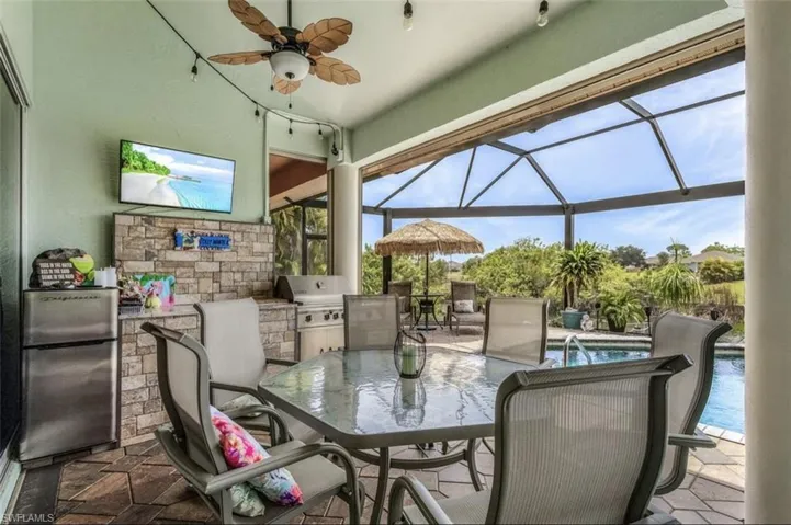 View of patio / terrace featuring area for grilling, ceiling fan, an outdoor kitchen, and glass enclosure